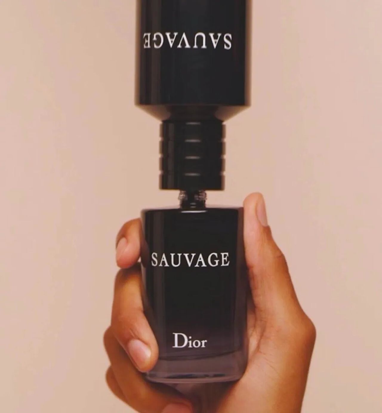 一手拿著Dior Sauvage香水瓶，將補充裝倒置在上面，以需簡單一步即可把Sauvage香水重新注滿。 